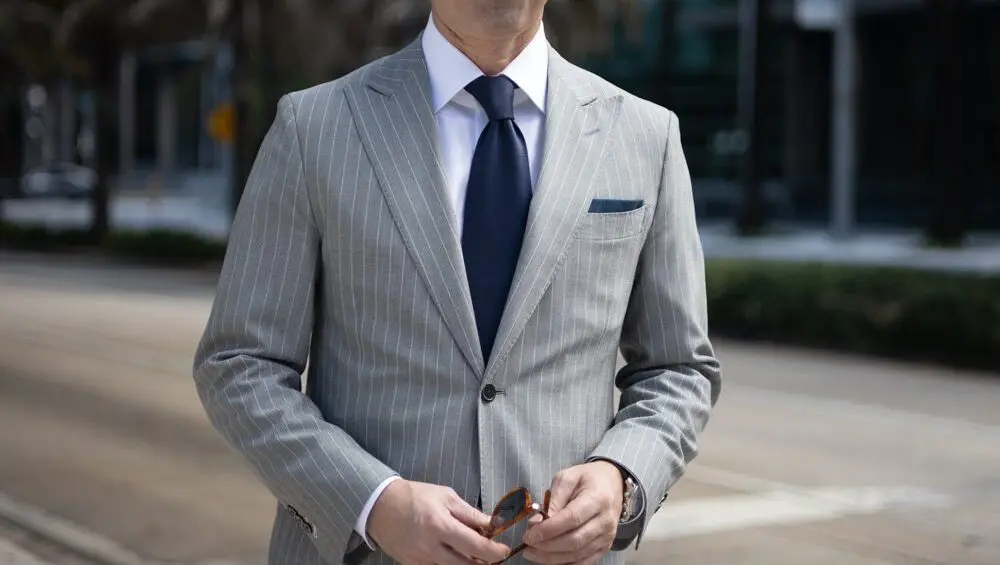 A man in a suit and tie standing on the side of a road.