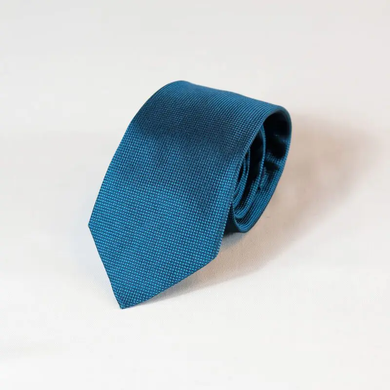 A blue tie is laying on the ground.