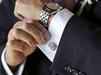 A man in a suit and tie fixing his cuff.