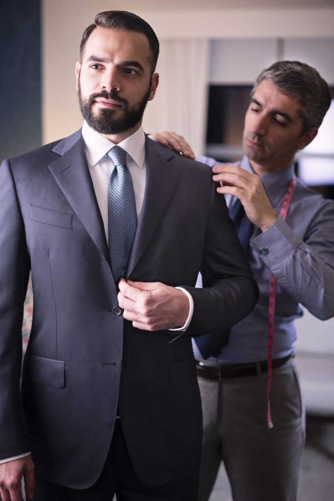 A man in suit and tie adjusting another mans jacket.