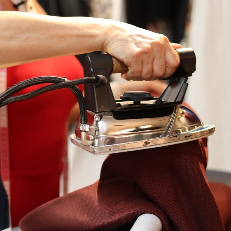 A person using an iron on the seat of a car.