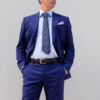 A man in blue suit and tie standing with his hands in his pockets.