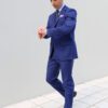 A man in blue suit and tie standing on tiled floor.