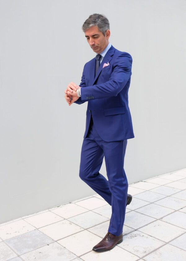 A man in blue suit and tie standing on tiled floor.