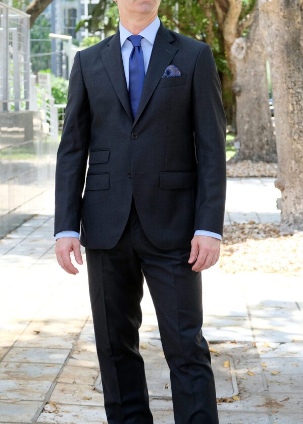 A man in suit and tie standing on sidewalk.