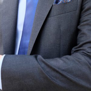 A man in suit and tie with his hands crossed.