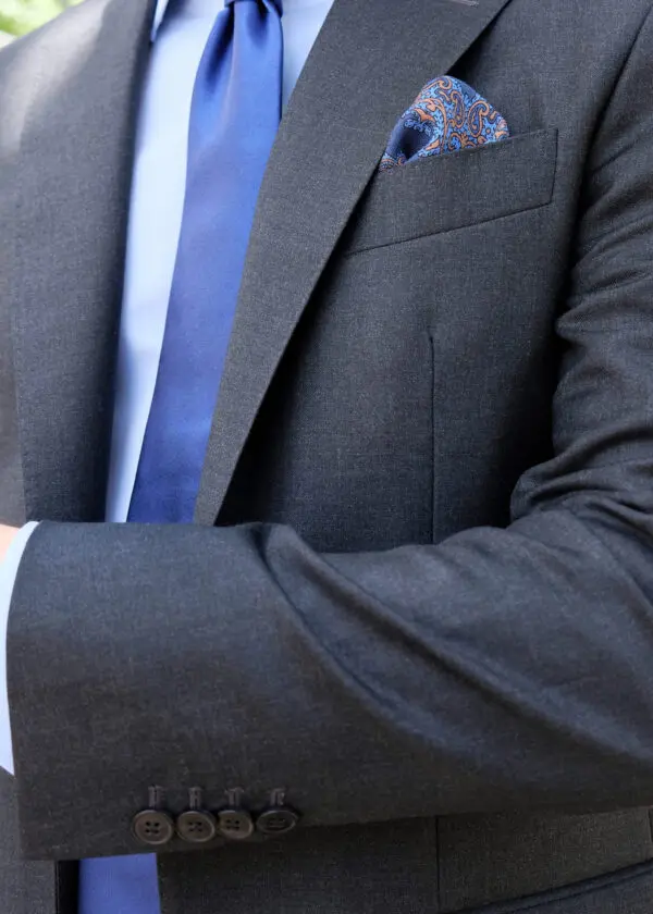 A man in suit and tie with his hands crossed.