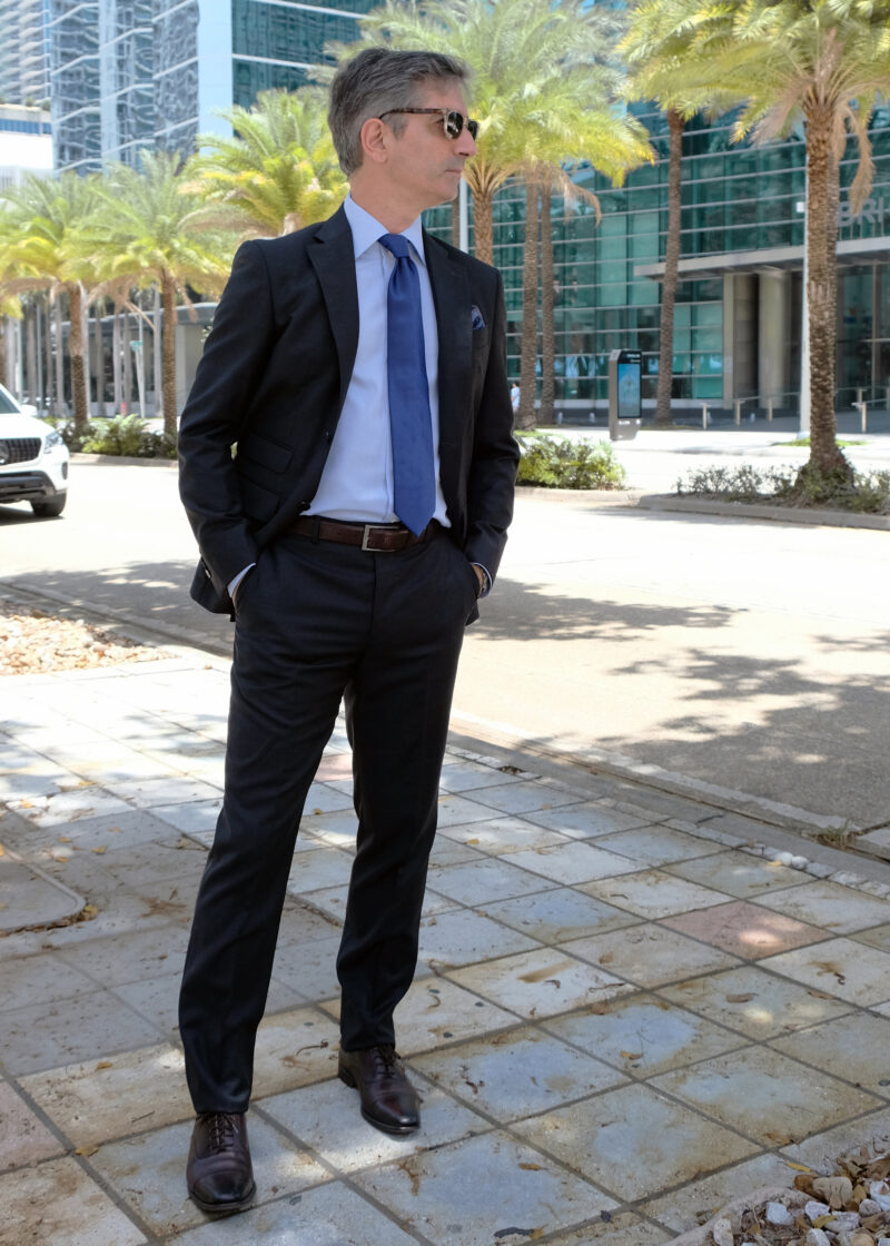A man in suit and tie standing on the sidewalk.
