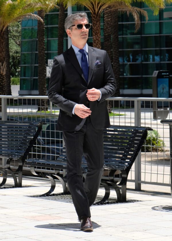 A man in suit and tie walking on sidewalk.