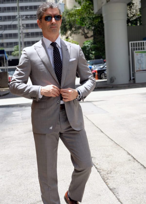 A man in a suit and tie standing on the sidewalk.