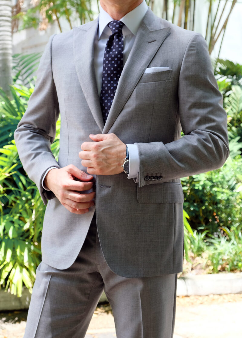 A man in a suit and tie putting on his watch.