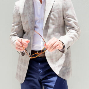 A man in a suit and tie holding his glasses.