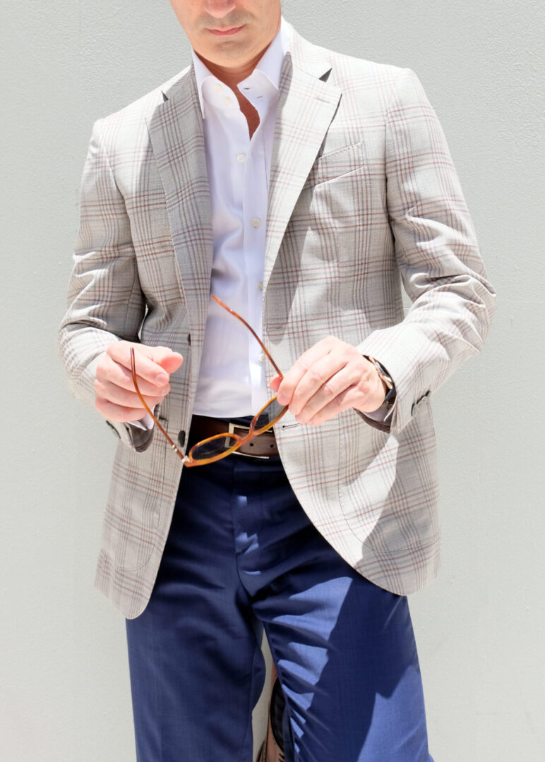 A man in a suit and tie holding his glasses.