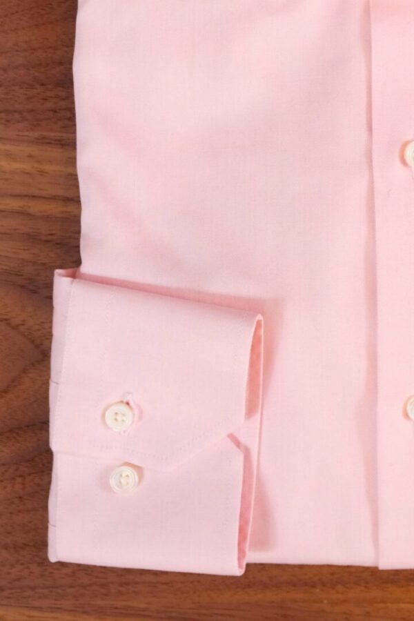 A pink shirt is shown with two white buttons.