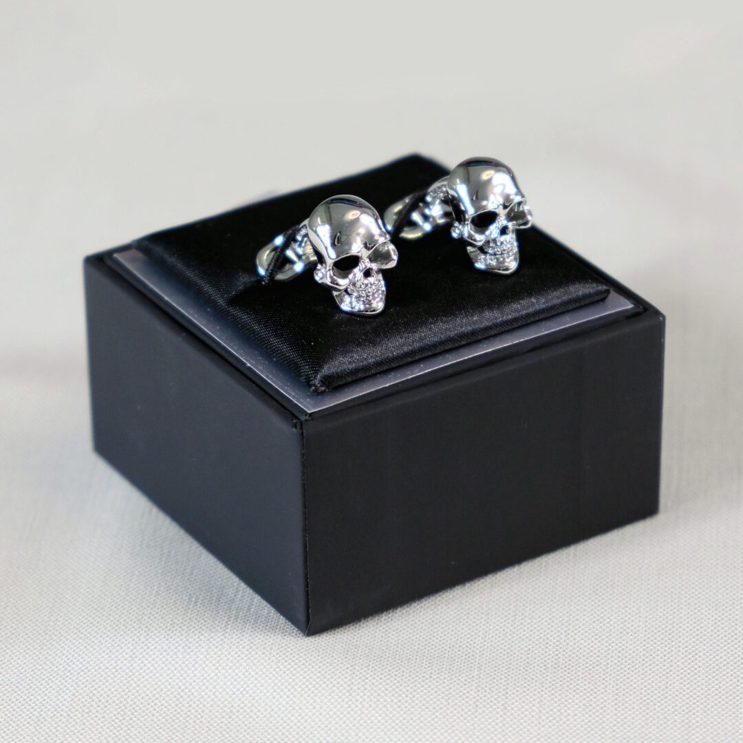A black box with two silver skull cufflinks.