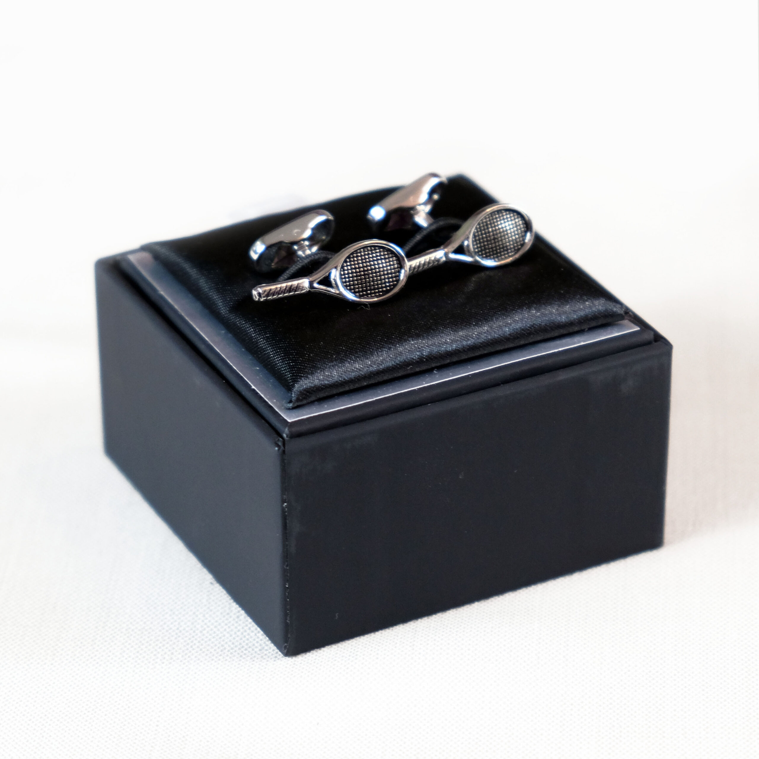 A black box with two cufflinks and one tie clip.