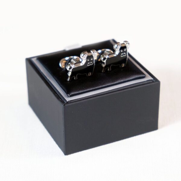 A black box with two silver cufflinks in it.