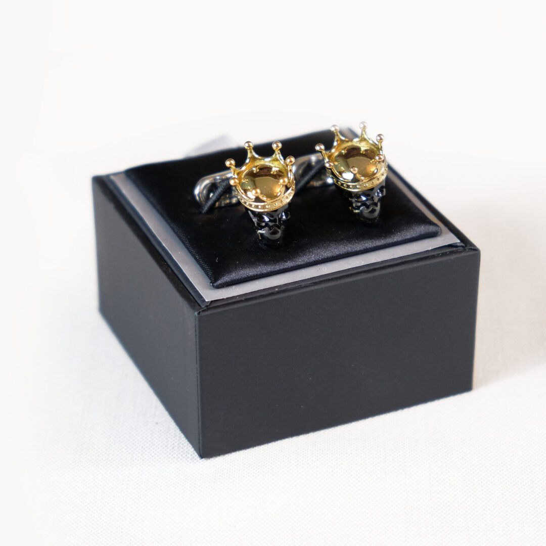 A black box with two gold plated cufflinks in it.