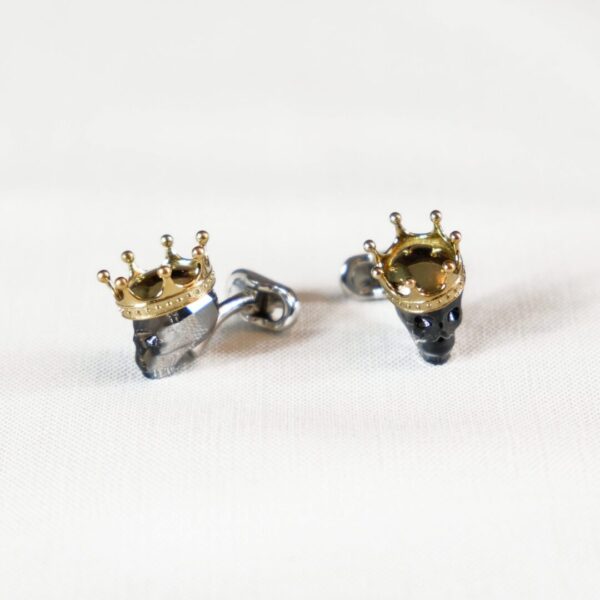 A pair of earrings with gold crowns on them.