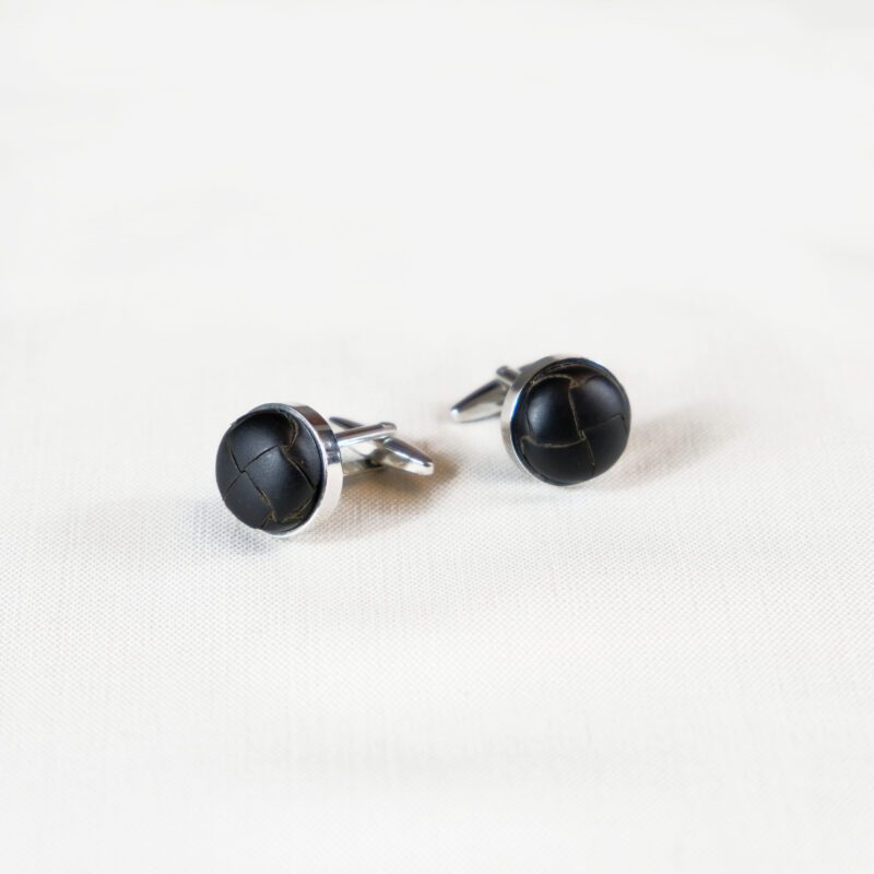 A pair of black cufflinks on top of a white surface.