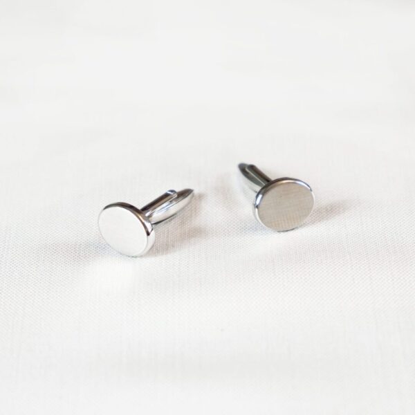 A pair of silver earrings sitting on top of a table.