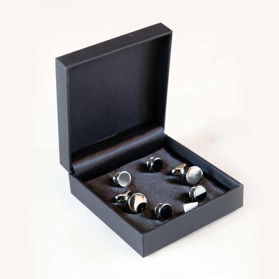 A set of six silver and black cufflinks in a box.