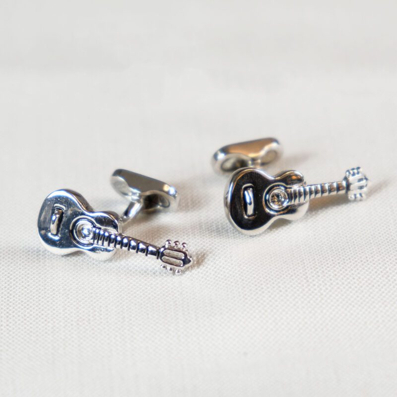 A pair of guitar cufflinks on top of a table.