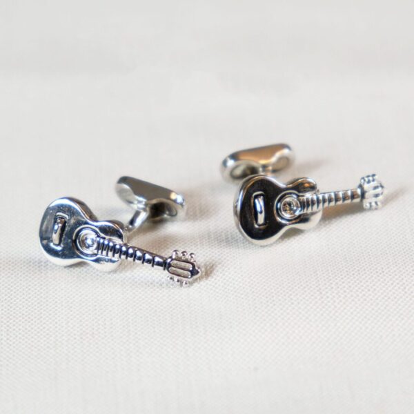 A pair of guitar cufflinks with a screw and a black one.