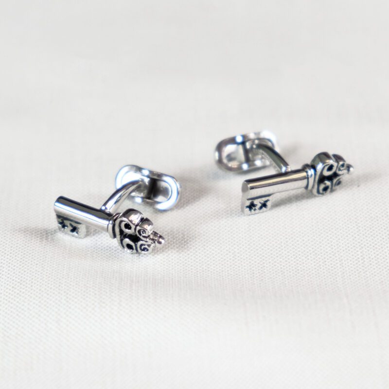 A pair of silver earrings with a key on them.