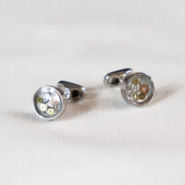 A pair of cufflinks with a silver and gold design.