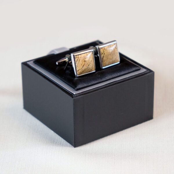 A pair of cufflinks in a box on top of a table.