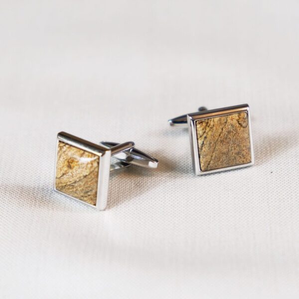 A pair of cufflinks with gold leaf on them.