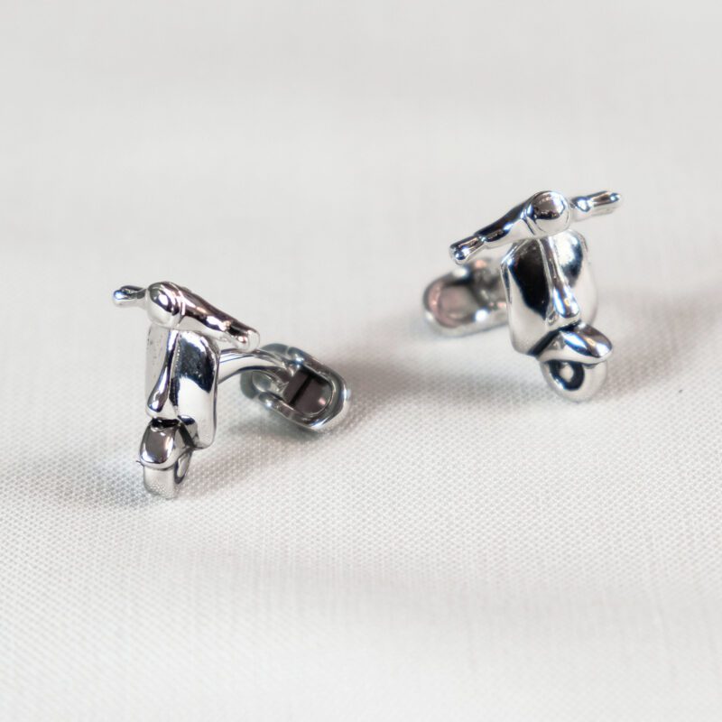 A pair of silver motorcycle cufflinks on top of a table.