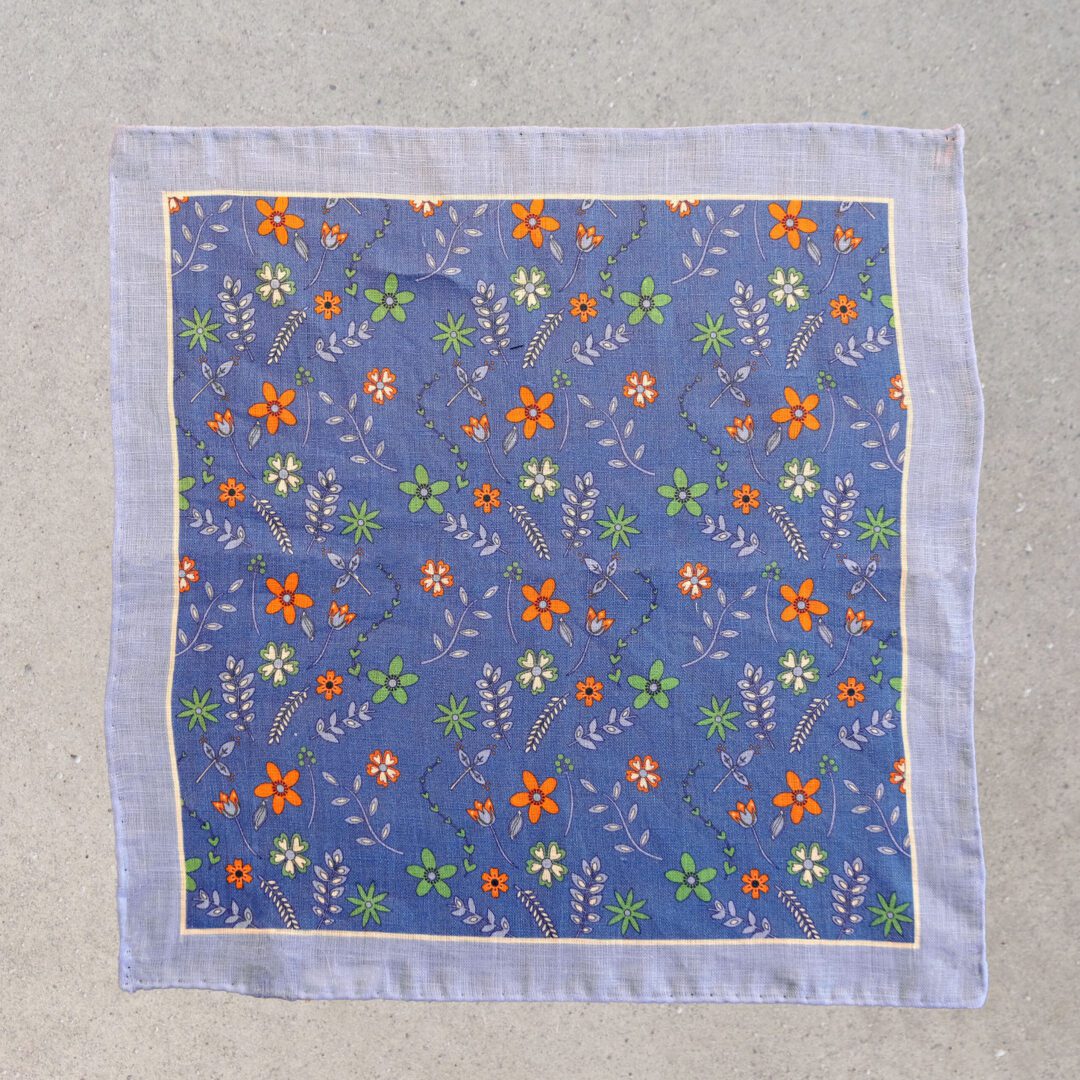 A blue square with orange and green flowers on it.