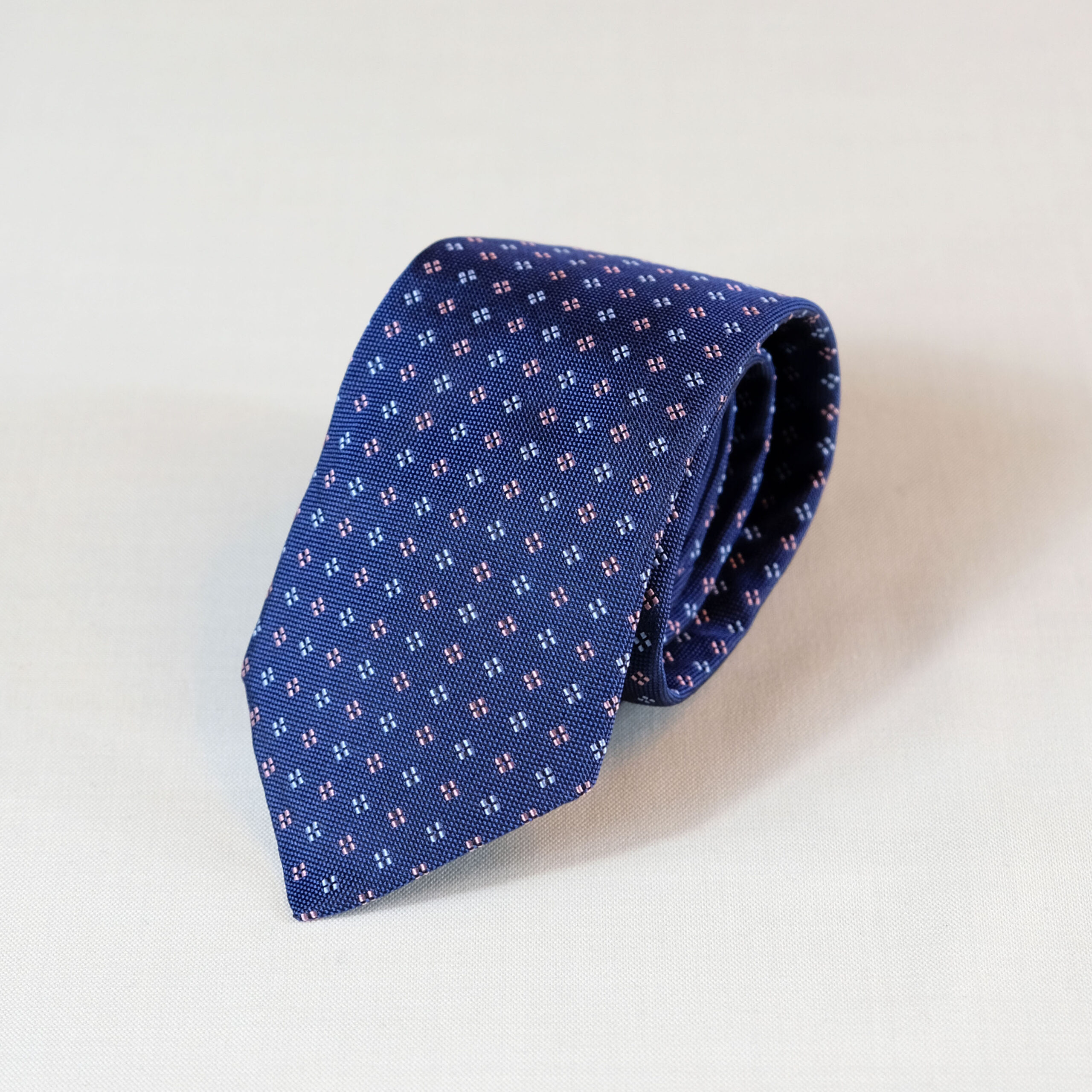 A blue tie with white and red squares on it.