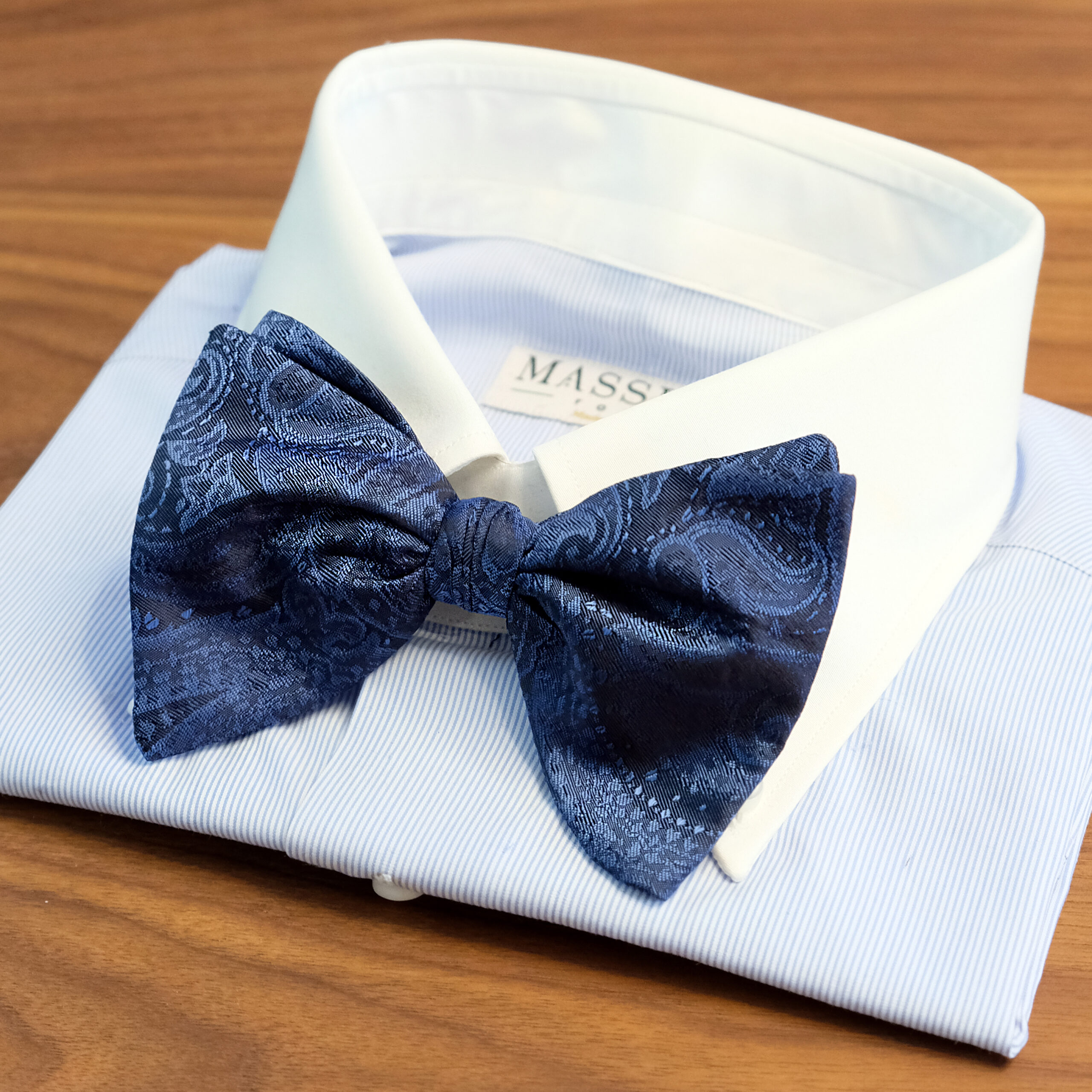 A bow tie is on the collar of a shirt.