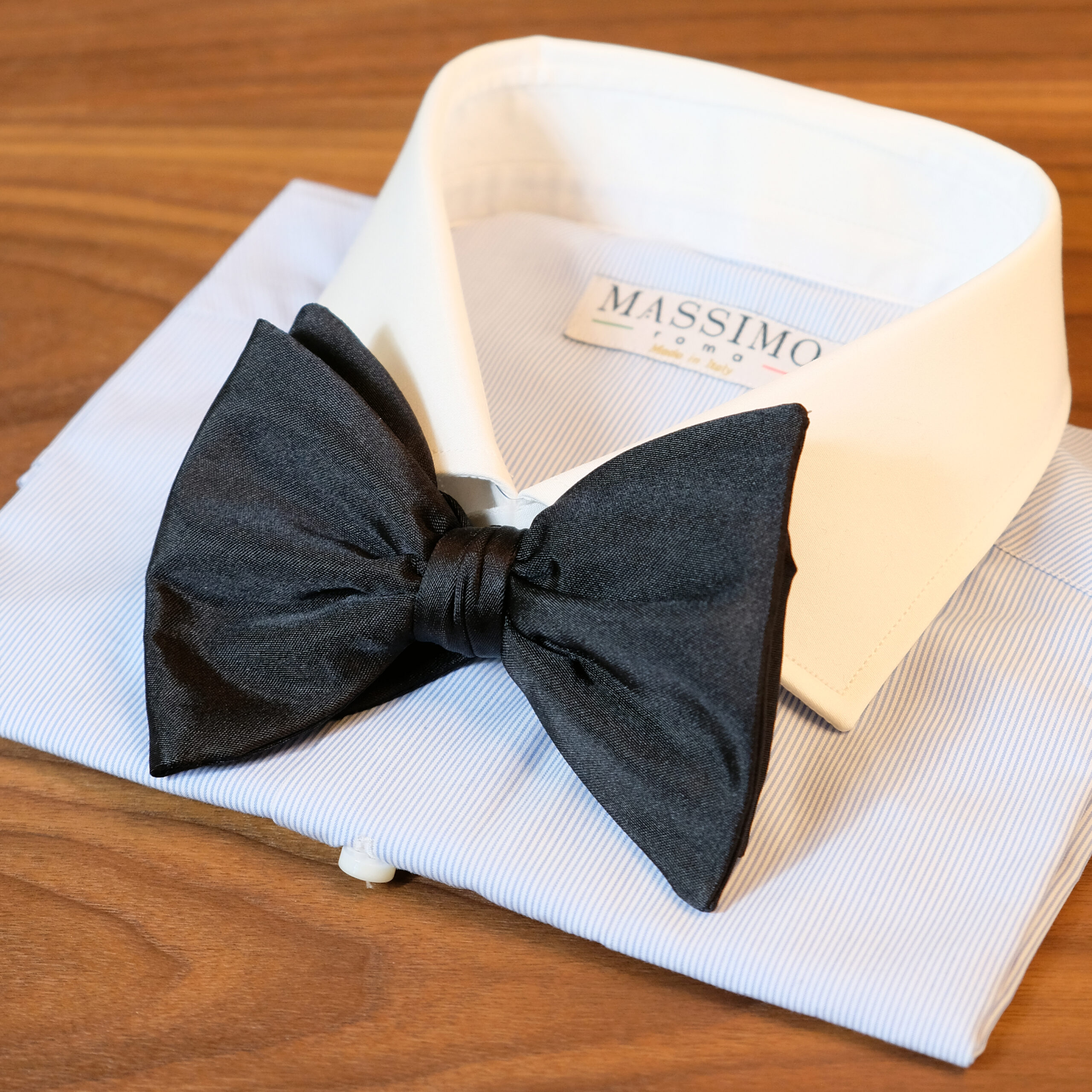 A black bow tie on top of a white shirt.