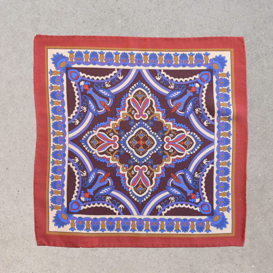 A square scarf with an intricate design on it.