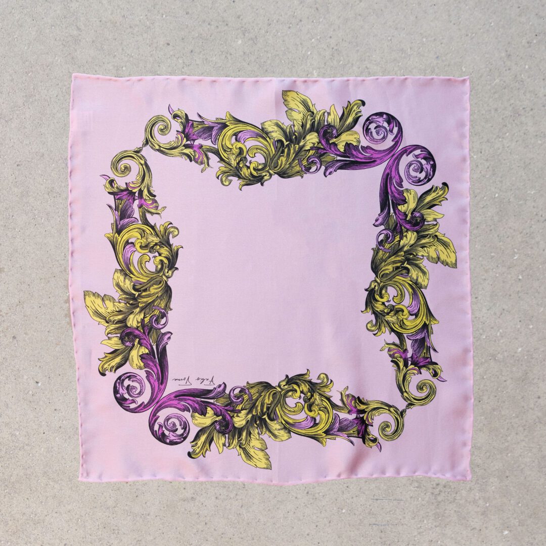 A purple and green floral print on a pink background.
