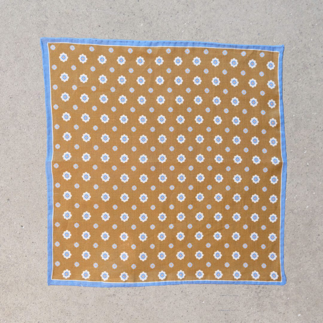 A square of paper with blue border and white polka dots.