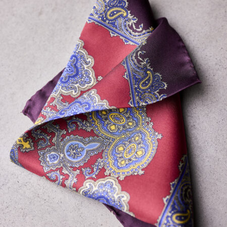 A folded red and purple paisley pocket square.