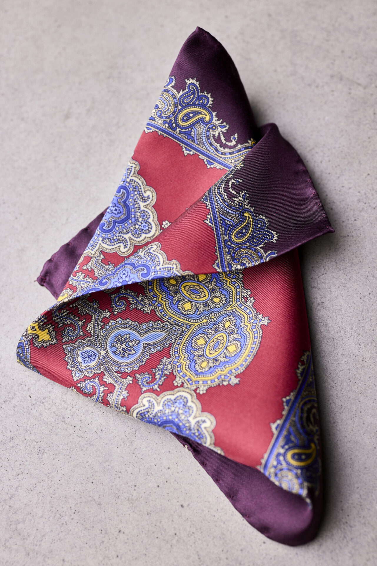 A folded red and purple paisley pocket square.