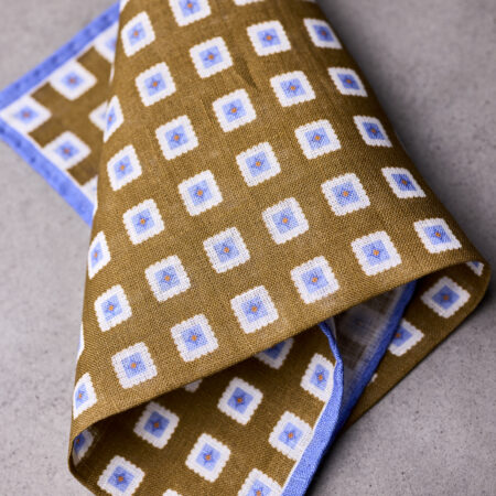 A folded brown and blue square patterned pocket square.