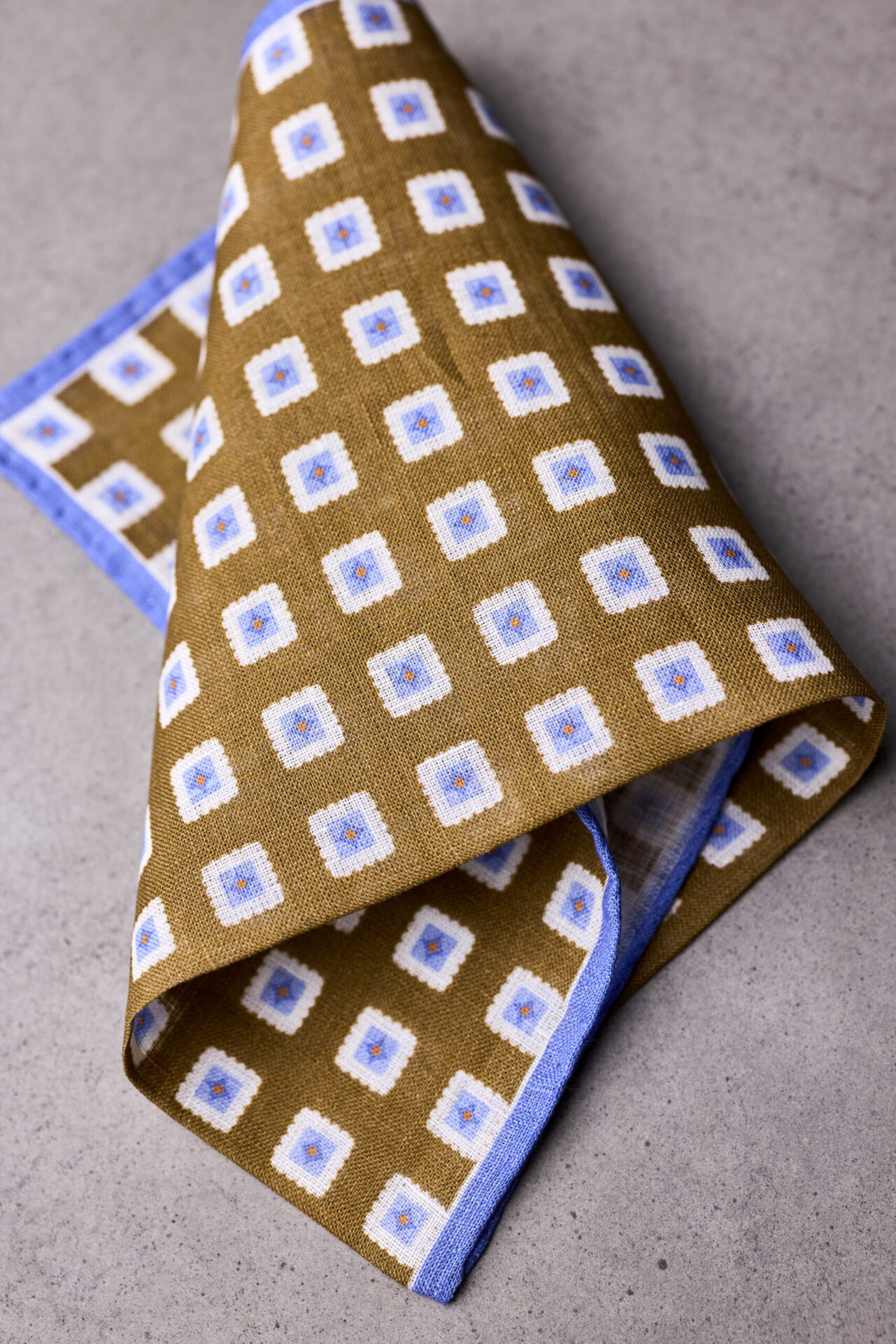 A folded brown and blue square pattern pocket square.