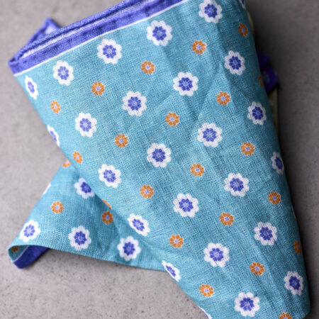 A blue and white floral print pocket square folded on top of it.