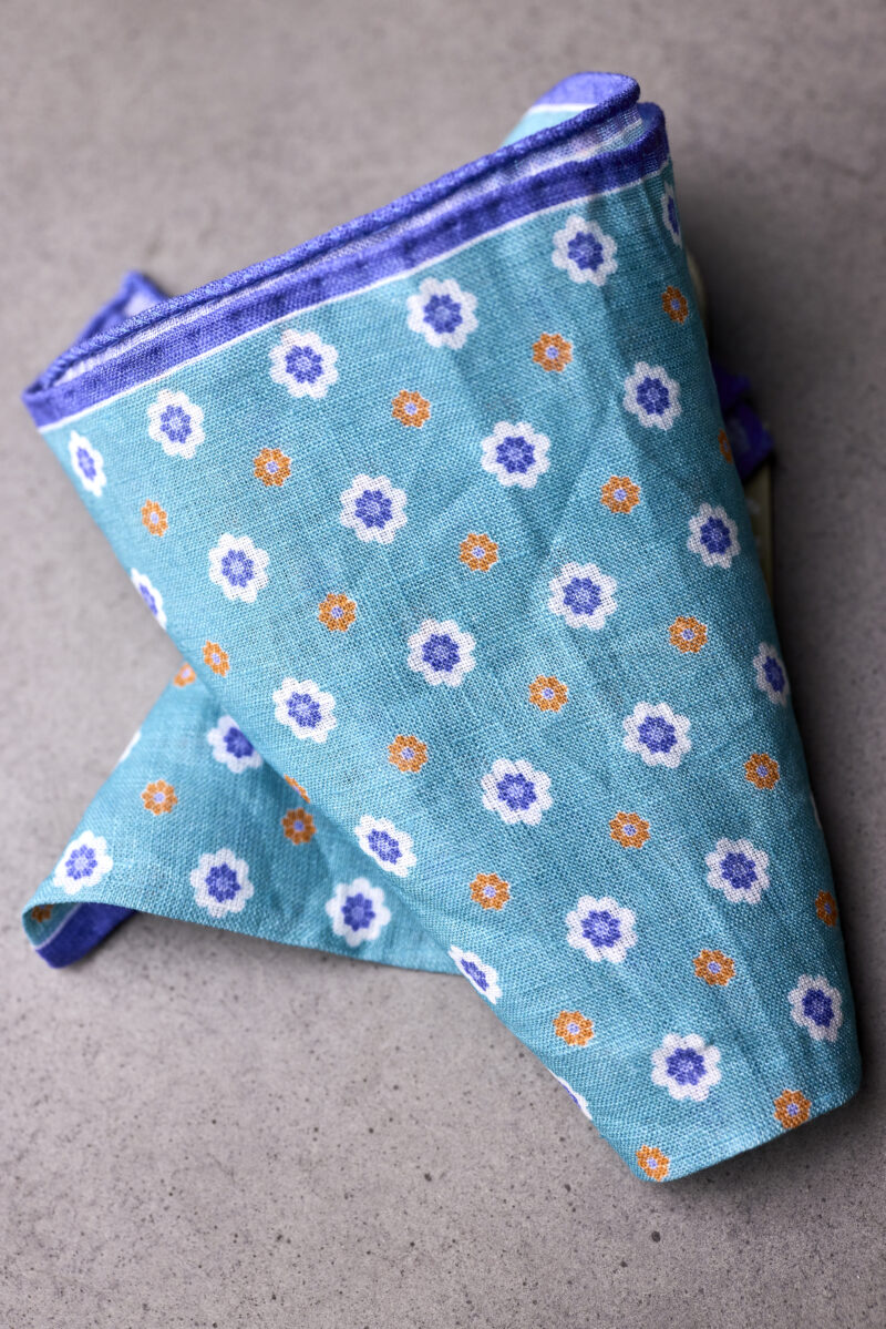 A blue and white floral print pocket square folded on top of it.