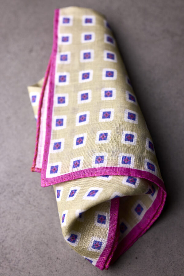 A folded yellow and purple pocket square with pink trim.