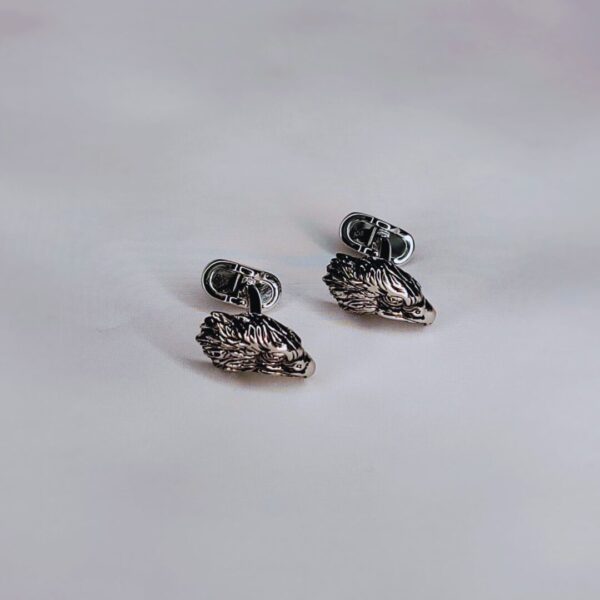 A pair of silver cufflinks with an animal design.