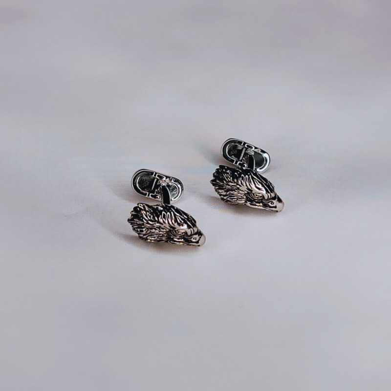 A pair of silver earrings on top of a table.