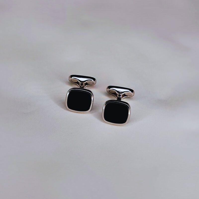 A pair of cufflinks on top of a white surface.